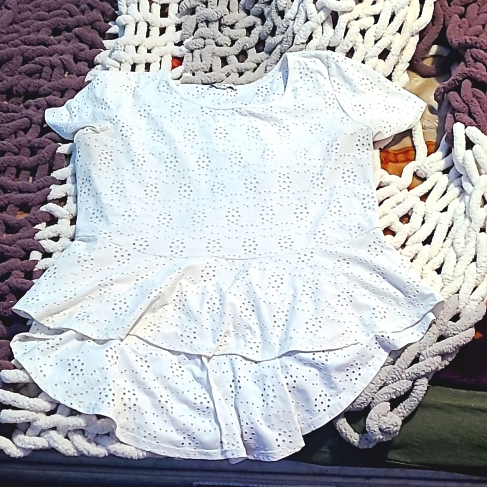 A short sleeve top, miniature holes in the shape of a flower, longer in the back
